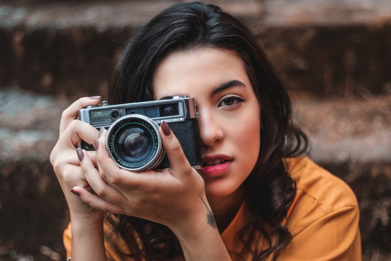 Frau mit Kamera in der Hand fotografiert sich selbst